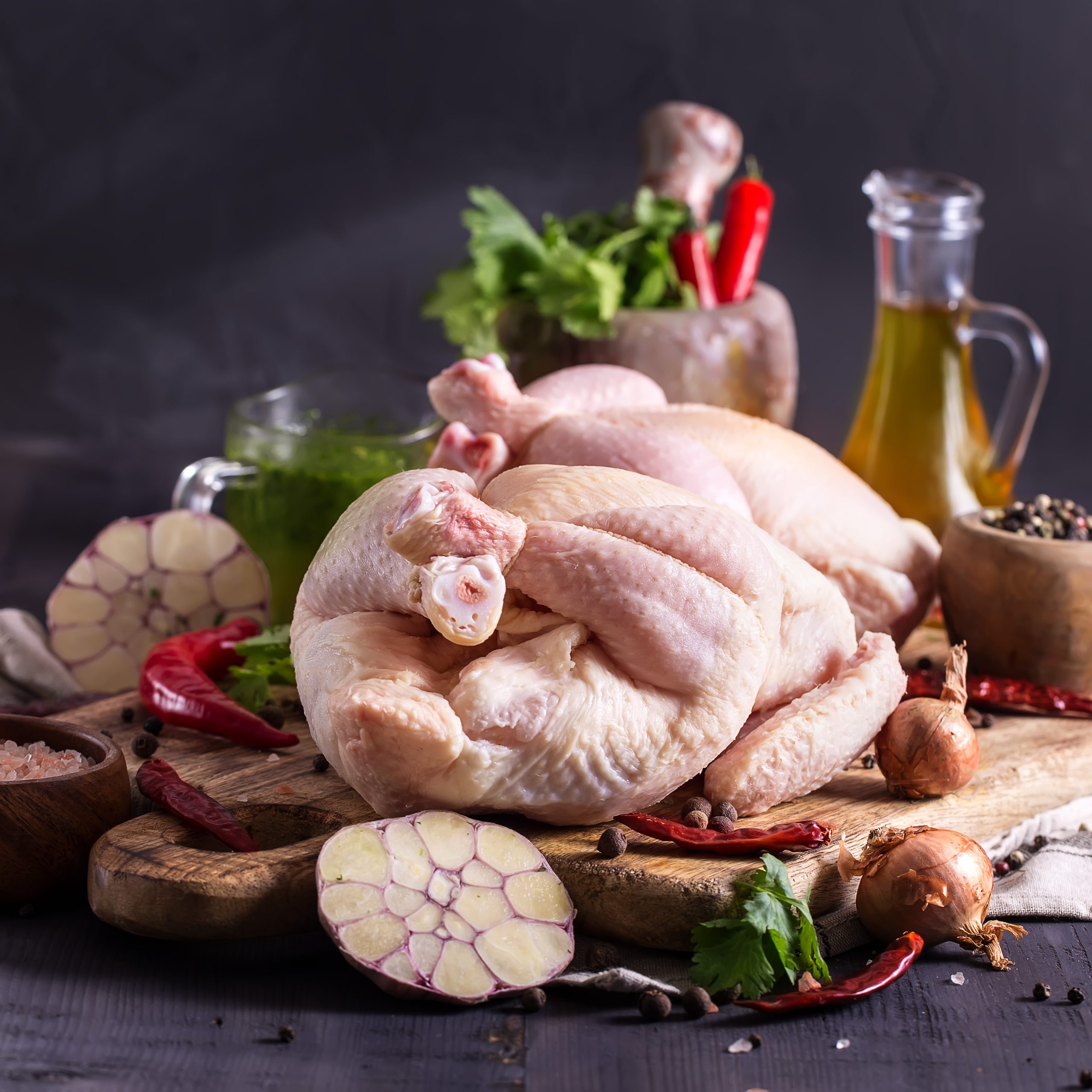 Two raw chickens on rustic wooden board with herbs and spices